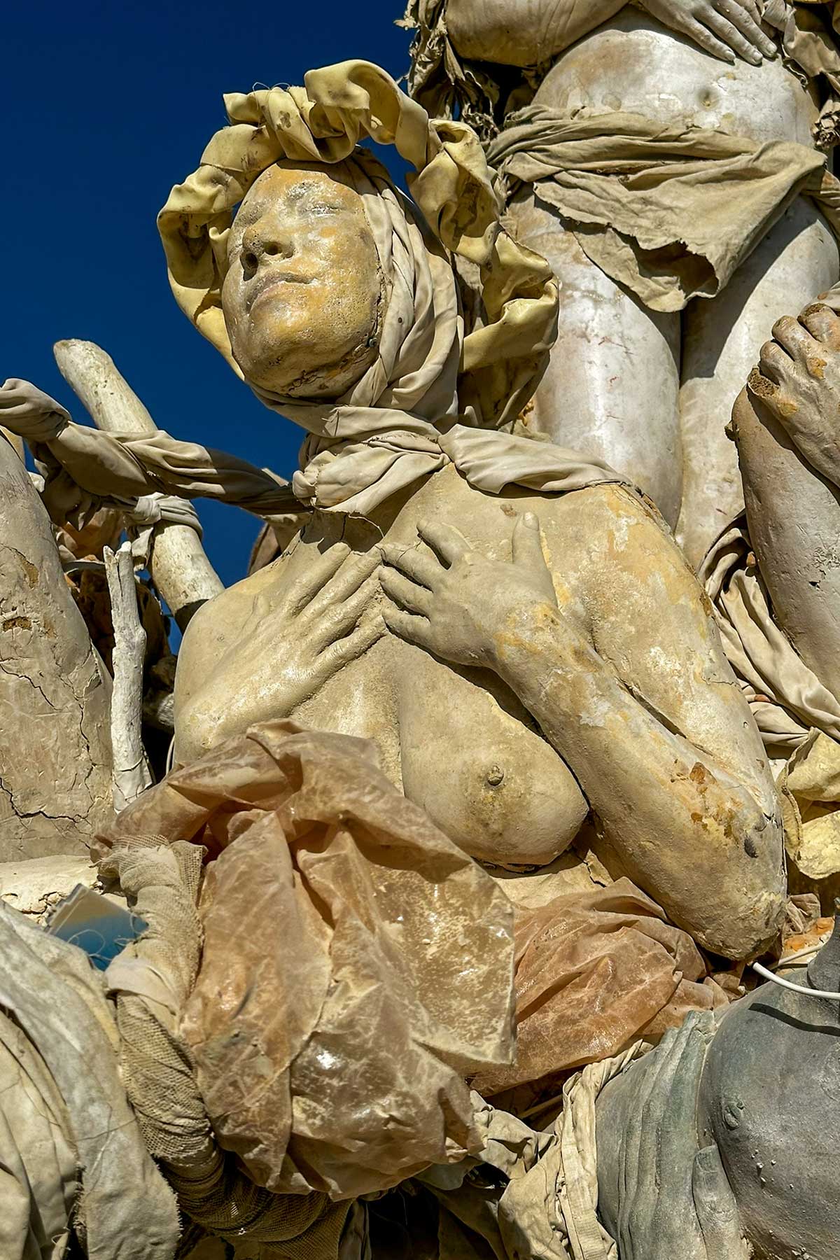 Close-up of a cast woman's face turned toward the sky, wrapped in sculpted fabric