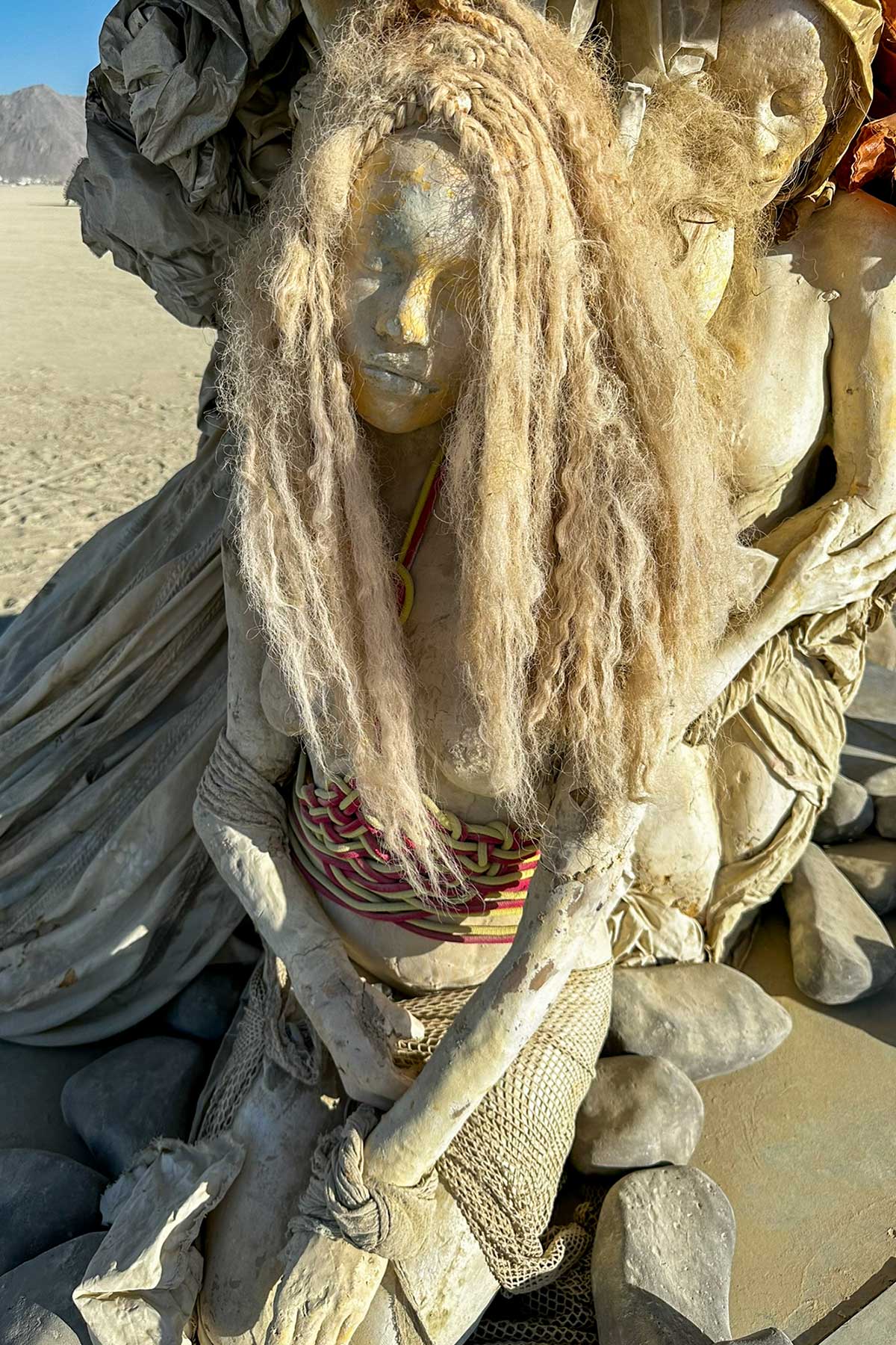 Close-up of a cast figure of a woman whose long, pale braided hair veils her face