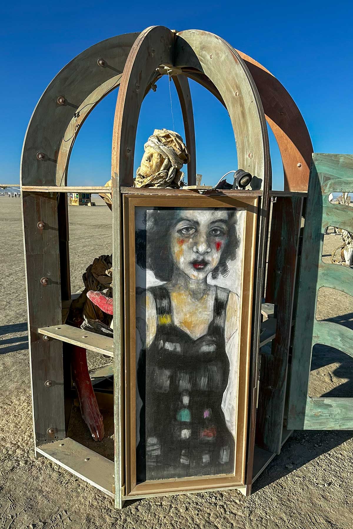 Domed wooden kiosk whose door shows a painted portrait of a dark-haired woman in a patterned dress